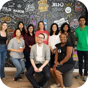 A group of people posing in front of a chalkboard wall.