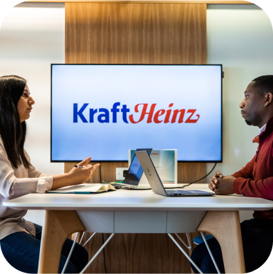 a man and a woman seated at a high table opposite each other with laptops in front of them