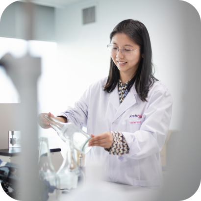 A woman in a lab coat holding a glass container.