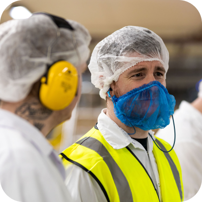 A group of people wearing protective gear in a factory.