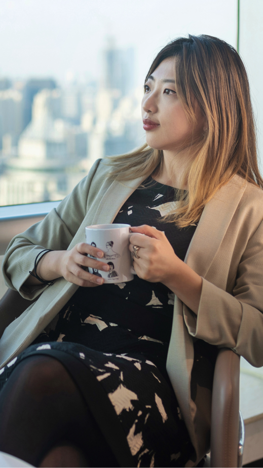 a woman sitting down and holding a mug in her hands