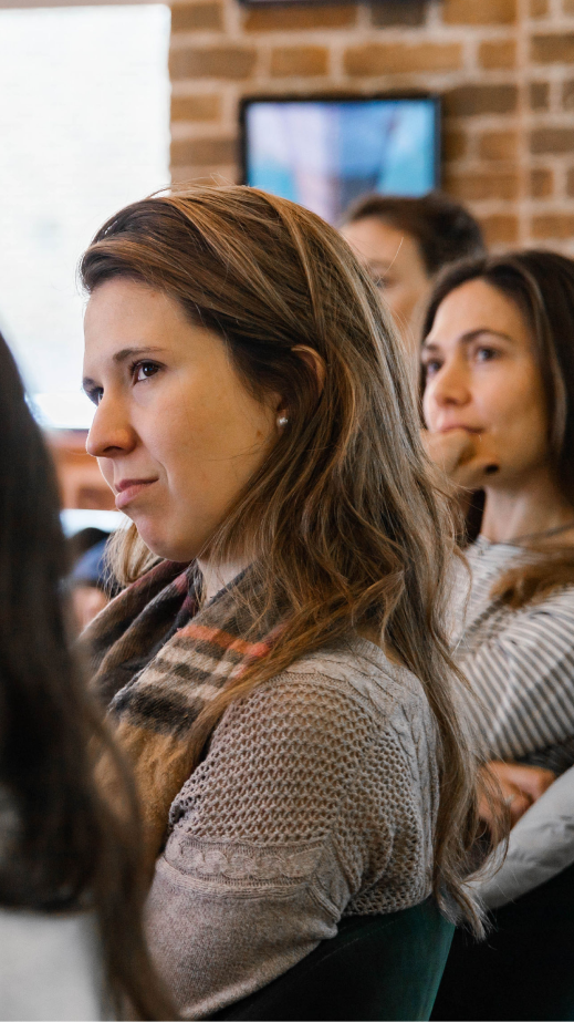 A group of people sitting at a table in an office and focusing on a presentation.