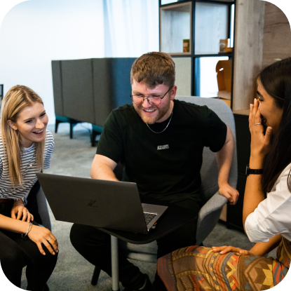 A group of people sitting around a laptop