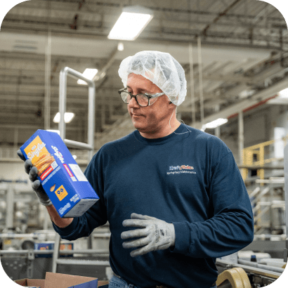 A male plant worker holding a Singles product box.